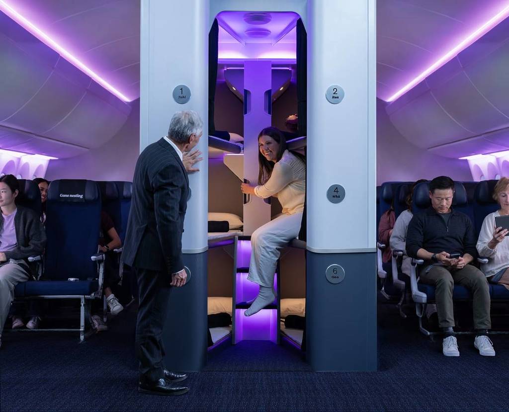 passenger leaving the middle bunk bed of Skynest while a flight attendant looks on