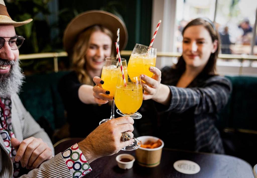 people clinking their cocktail glasses together at Trinity