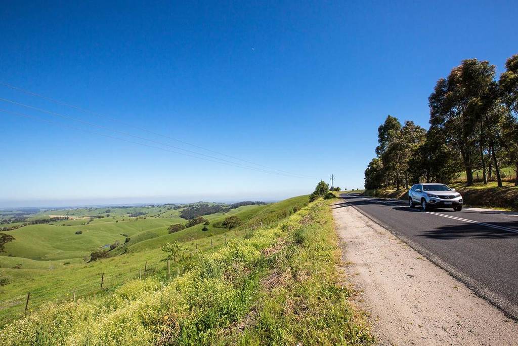 car driving along the Grand Ridge Road, with rolling green hills to the side