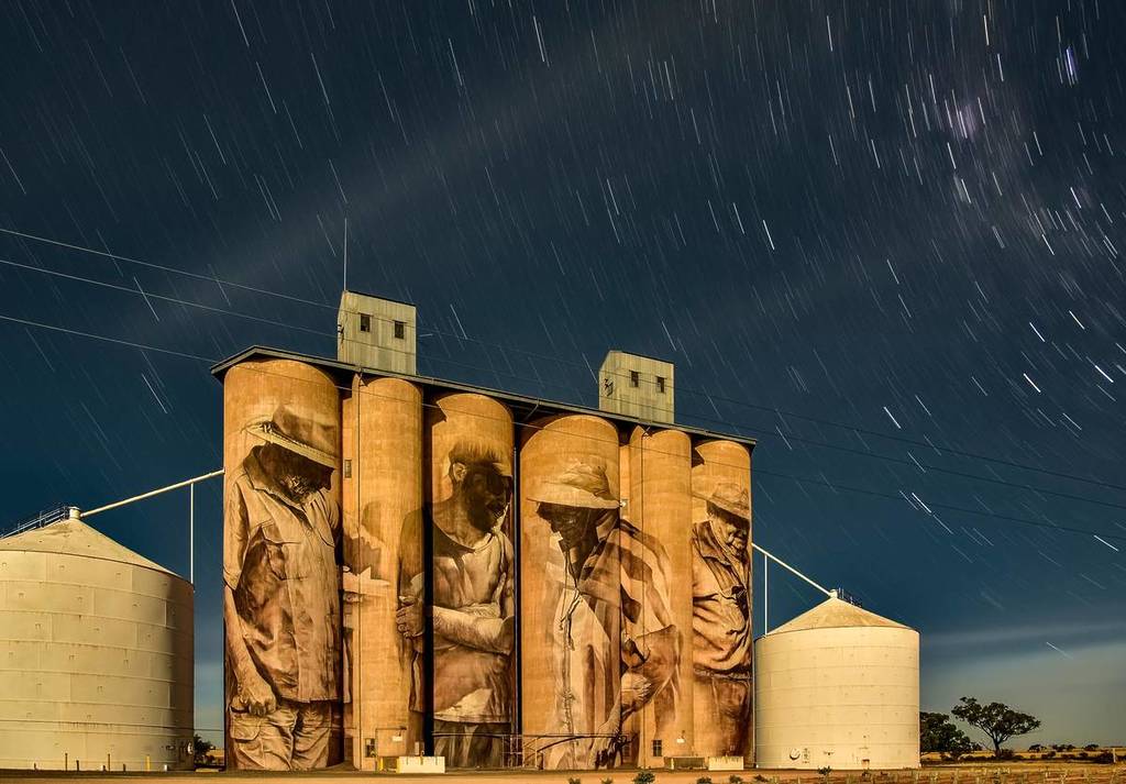 artwork on a grain silo on the Silo Art Trail at night, with stars whirling above