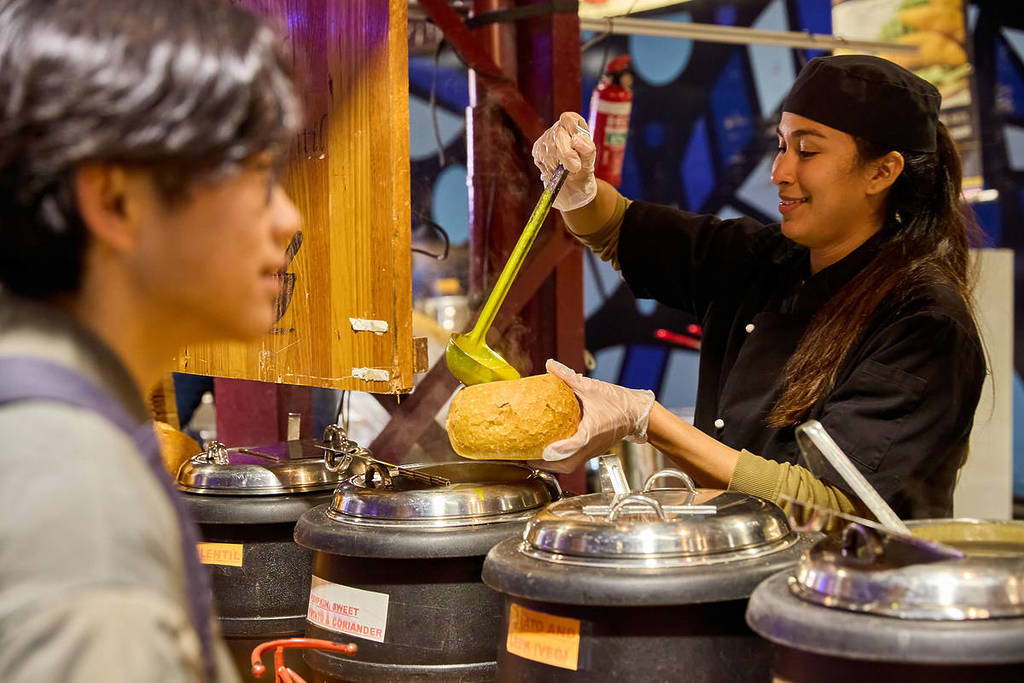 woman pouring soup into a bread bowl at Winter Night Market