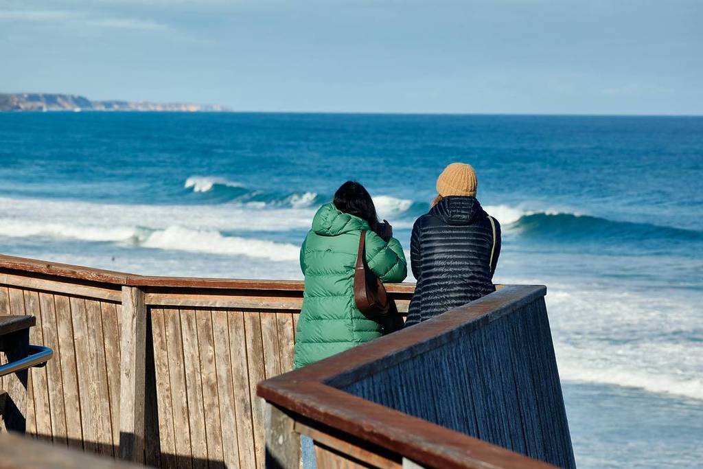 two people in big jackets looking for whales from the Logans Beach platform in Warrnambool