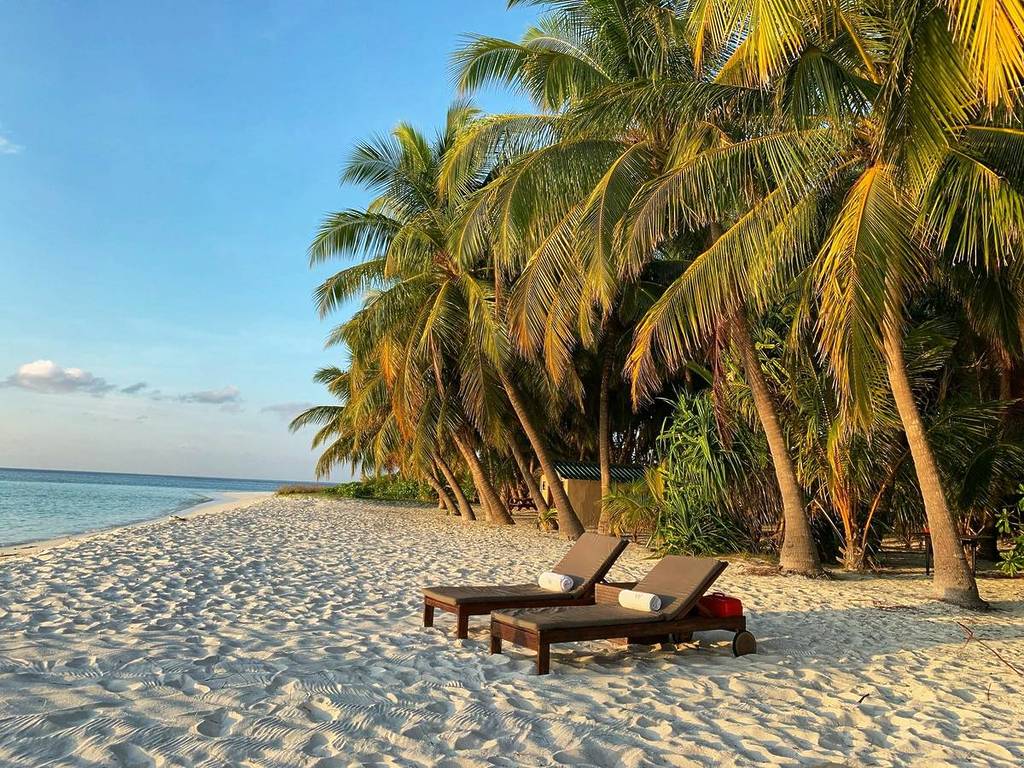 lounge chairs on a beach at sunset in the Maldives