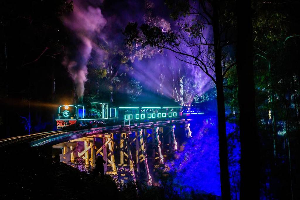 Train of Lights by Puffing Billy Railway lit up in blue and crossing a trestle bridge