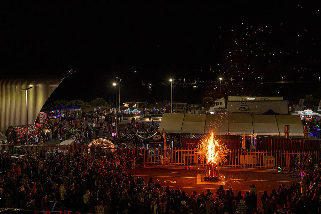 people gathered around a wood sculpture burning at Nightide