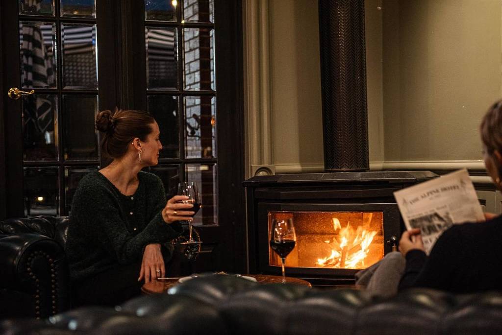 woman sipping on wine next to fireplace at Alpine Hotel in Warburton