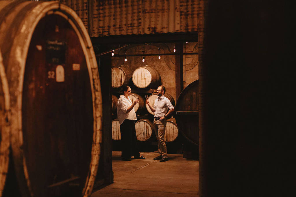 A man and a woman chat over a glass of wine inside a cellar at Dark Side of Wine Festival.
