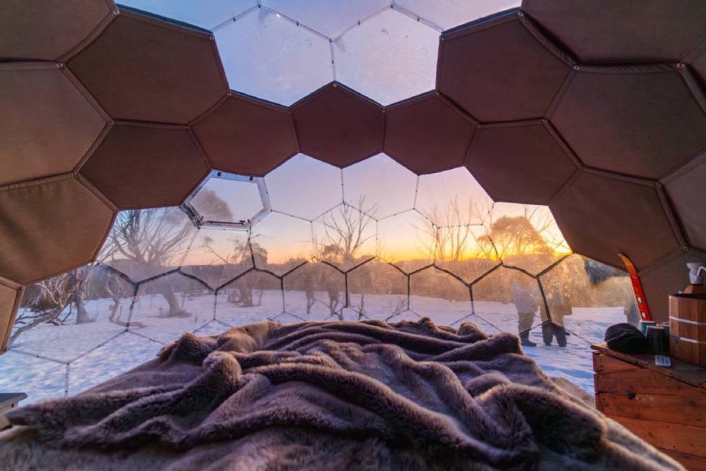 inside one of the domes from Alpine Nature Experience, looking out at a snowy landscape at either dawn or dusk