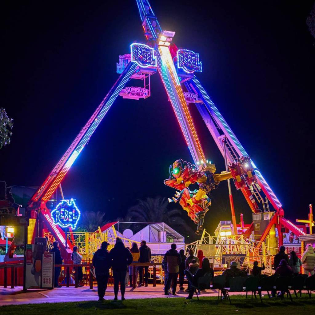people at Gumbuya World at night, with the rides lit up