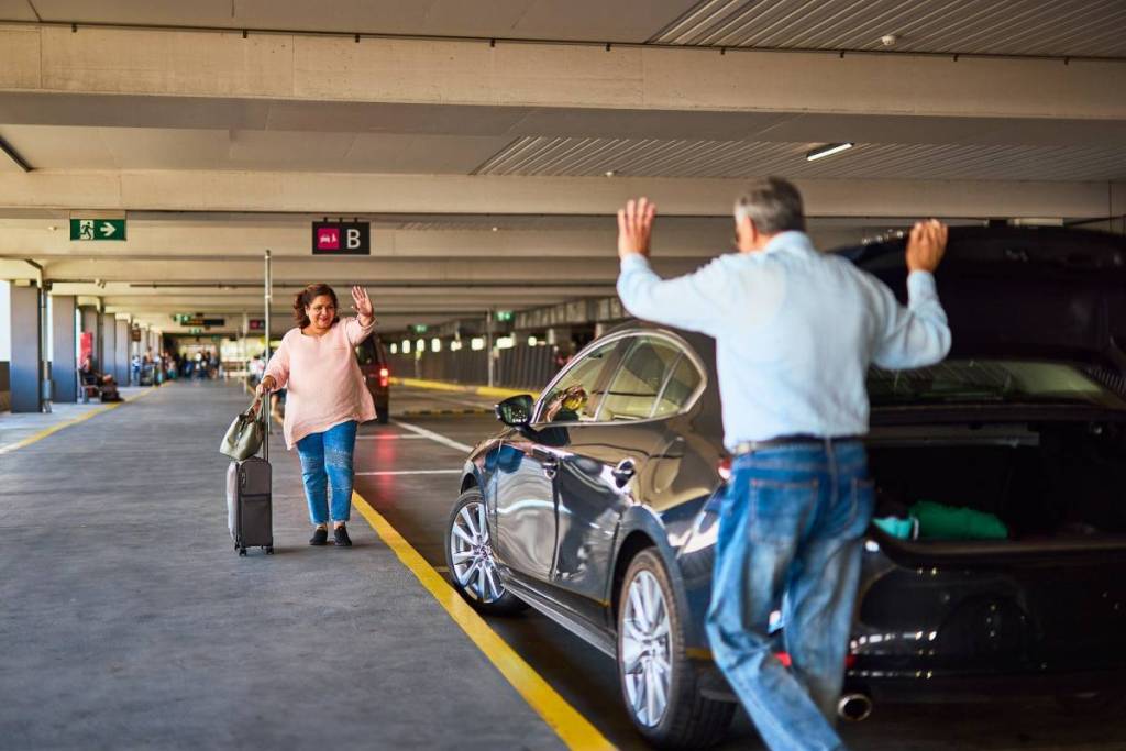 happy man greeting a female passenger at a pick up zone in Melbourne Airport