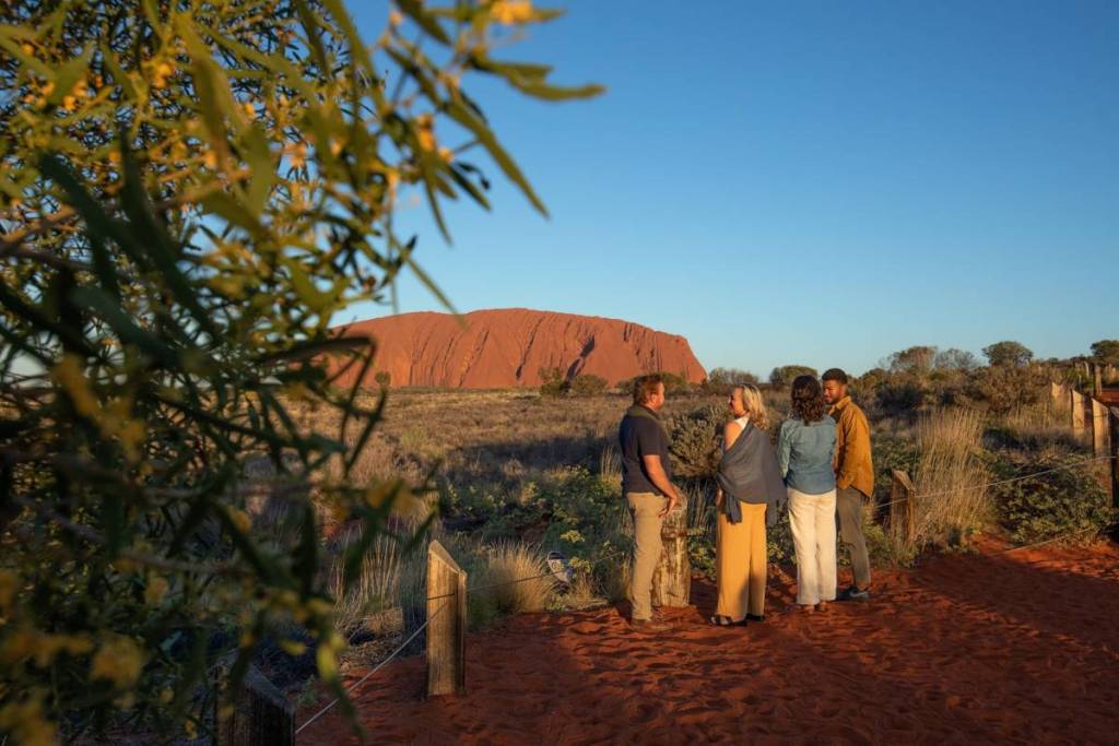 four people having a chat with Uluru in background