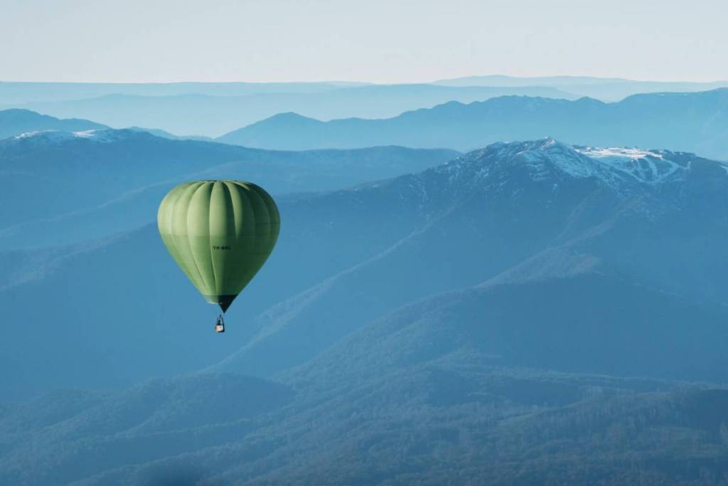 a hot air balloon in front of the snowy peaks of the High Country mountains