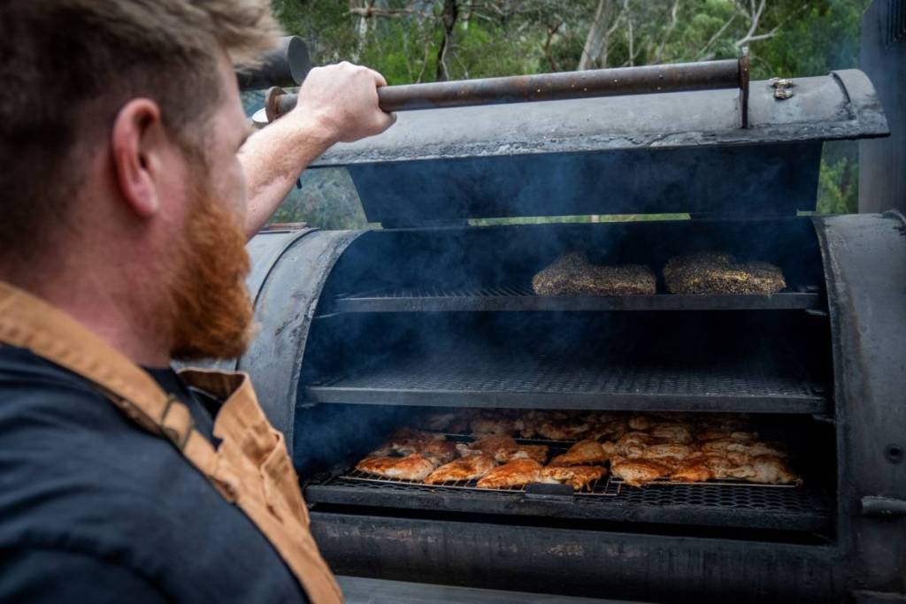 man looking at meat in a smoker for Grampians BBQ Festival