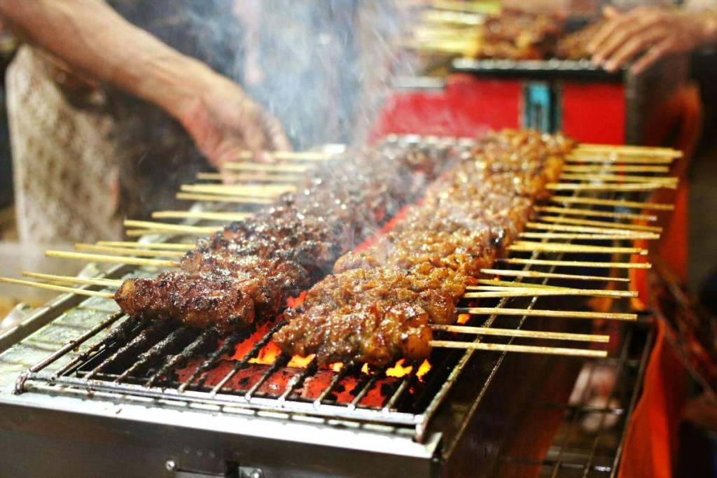 chicken and beef satay skewers cooking, to depict what you might see at the Malaysian Night Market