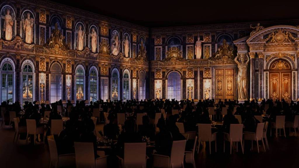 people dining at Chateau Merveilles, with projections looking like the mirror room in Versailles