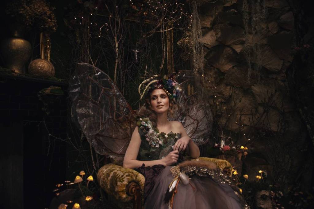woman dressed like a fairy in a low-lit themed space to represent the Dark Fae Masquerade Ball