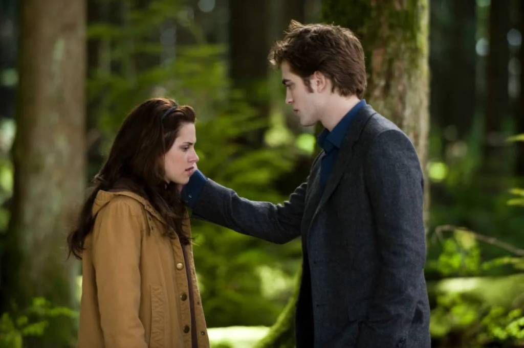 Edward holding the side of Bella's face, about to break up with her in the forest in New Moon