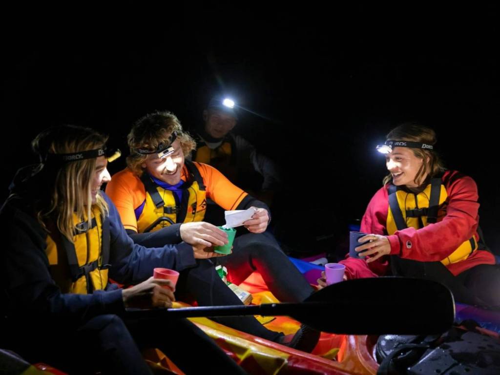 group of people in kayaks pausing for a hot drink at night
