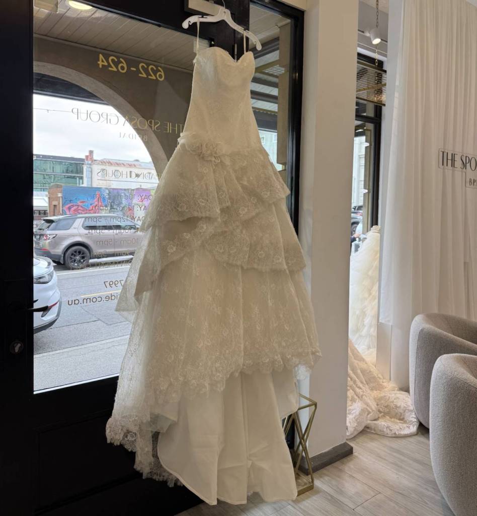 wedding dress hanging in front of the door at Sposa Bride shop