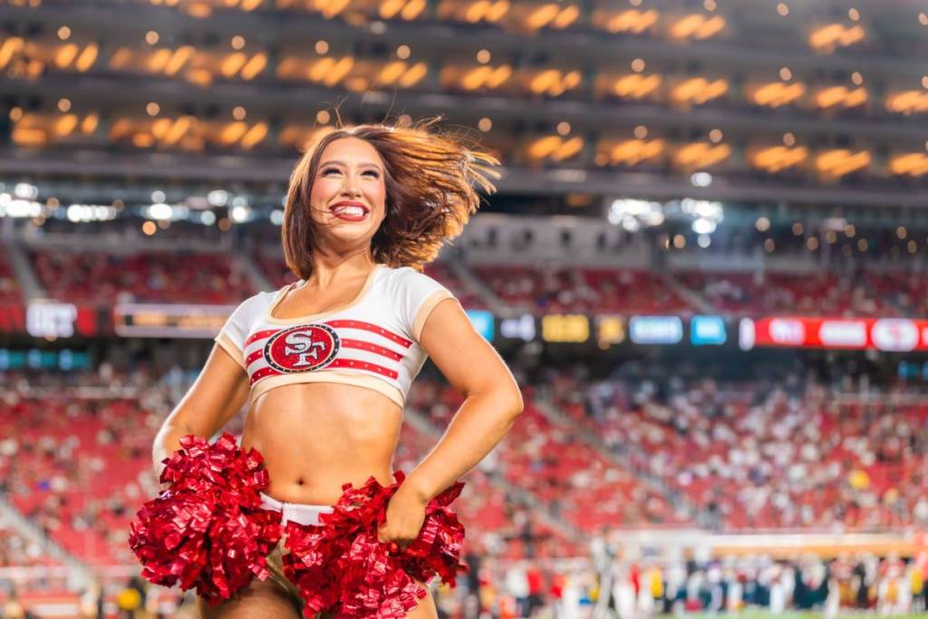 a 49ers gold rush cheerleader with hands on hips