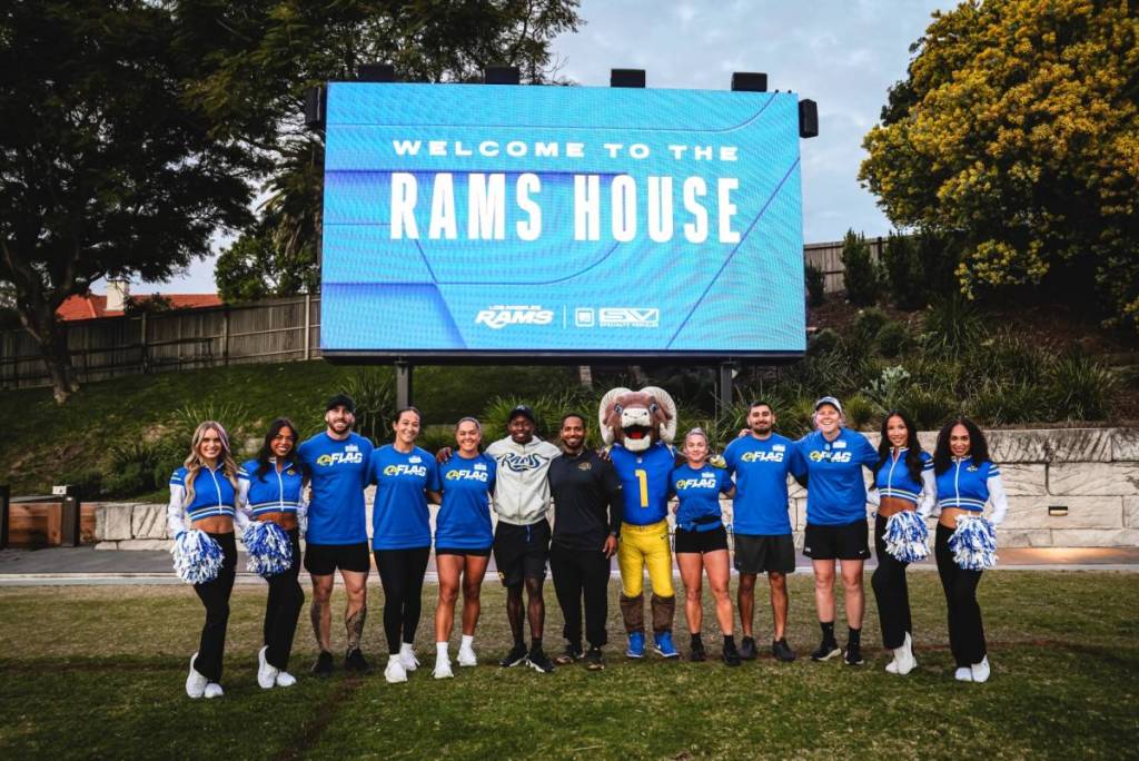 LA Rams players and cheerleaders in front of a sign that says Welcome to the Rams House