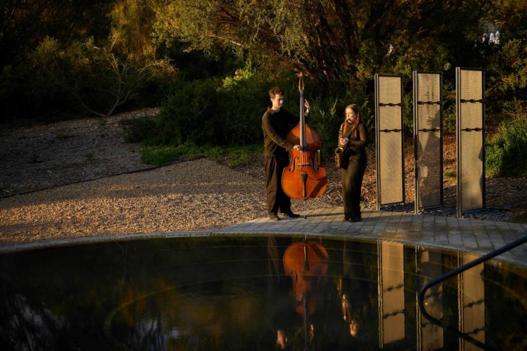 double bassist and saxophonist playing jazz by a geothermal pool at Alba Thermal Springs and Spa
