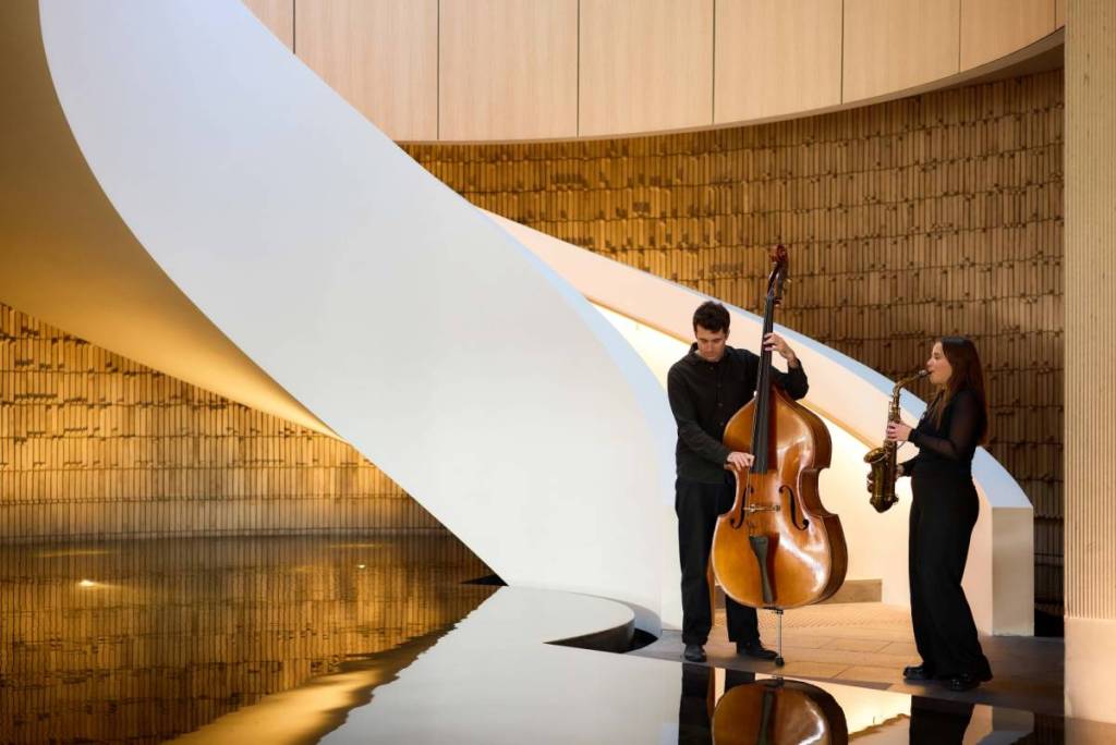 two musicians playing jazz in an indoor area at Alba, in front of a staircase
