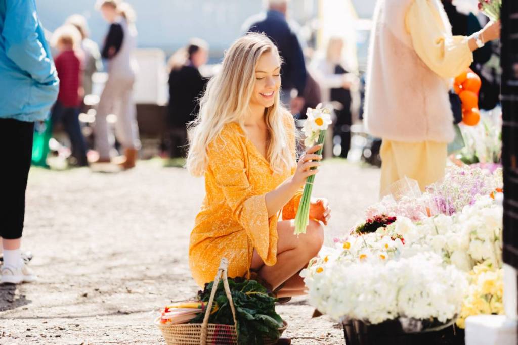 woman crouching and holding spring daffodils at the Kyneton Farmers Market