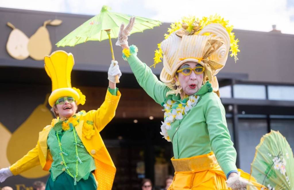 two colourful stilt walkers in yellow and green at the grand parade for Kyneton Daffodil & Arts Festival
