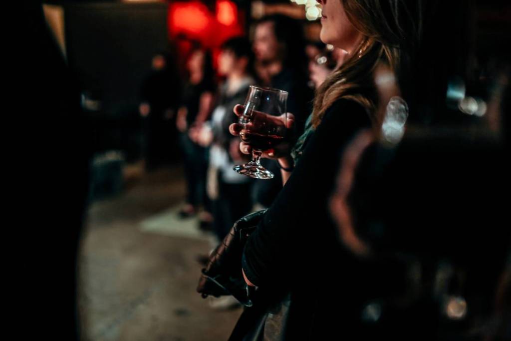 woman holding glass of wine while watching a gig