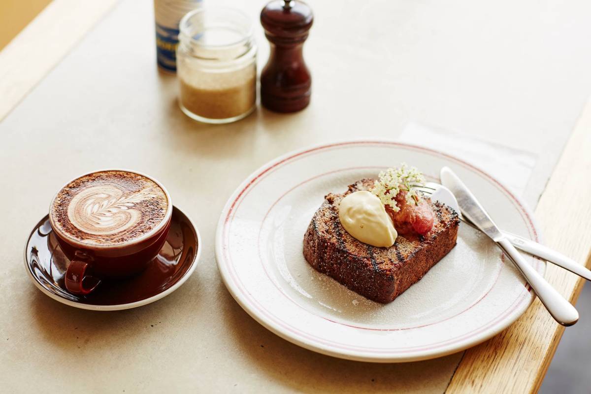 A cup of coffee with latte art and a plated sweet treat at a cafe in Lorne