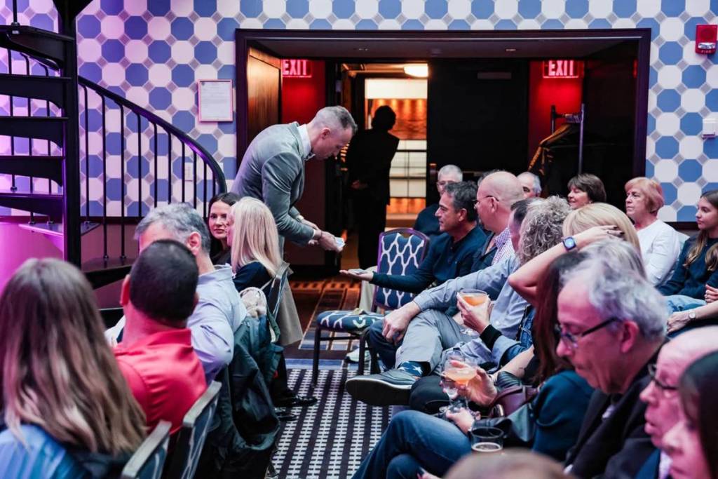 A man deals cards to the audience at Theatre of Magic.