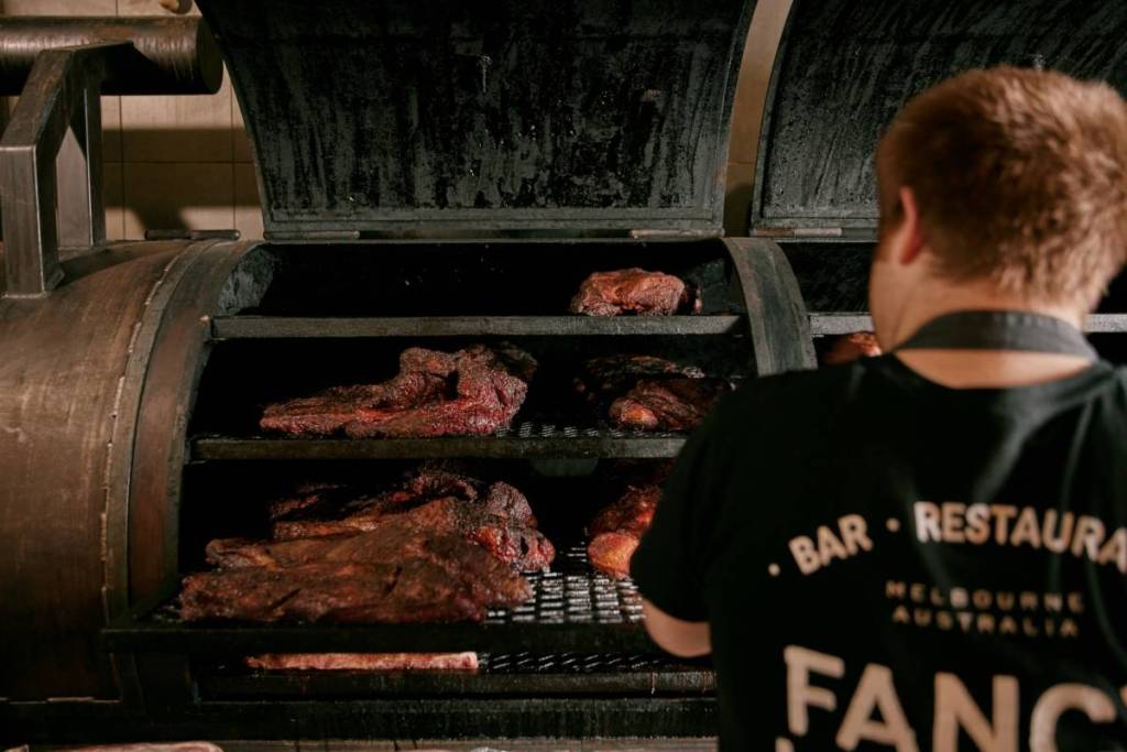fancy hanks chef slow cooking BBQ meat in a smoker