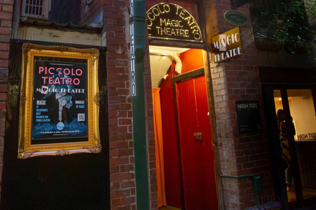 outside Piccolo Teatro, with a red door, a poster and a sign