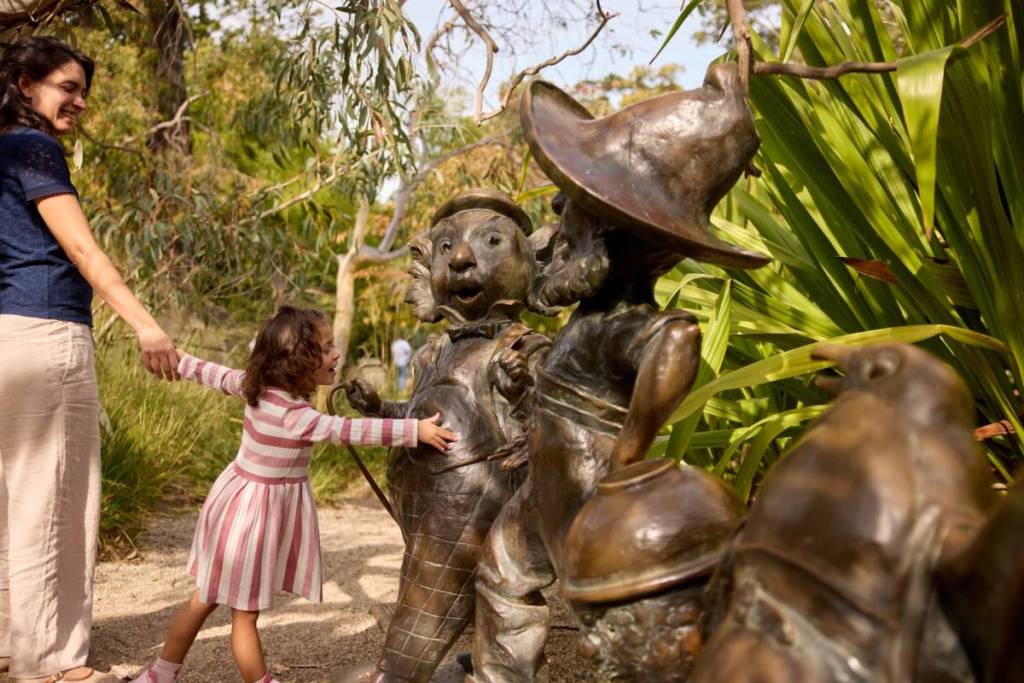 child reaching out to touch a statue in the Children's Garden at Royal Botanic Gardens Melbourne