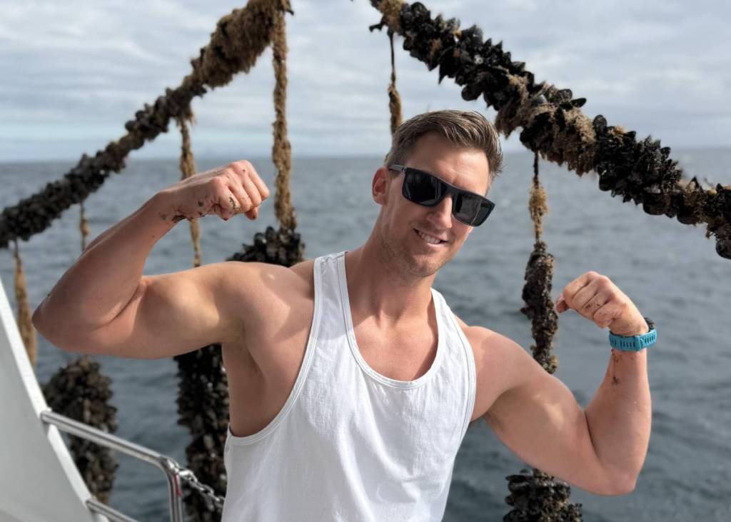 man flexing his muscles on a mussel boat in Portarlington