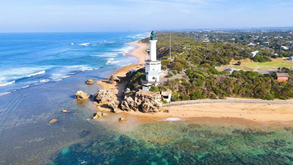 aerial view of Point Lonsdale lighthouse, with wild ocean waves on one side and calmer water on the other