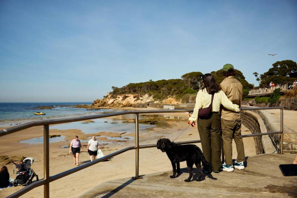 couple with dog looking at beach in Point Lonsdale at low tide