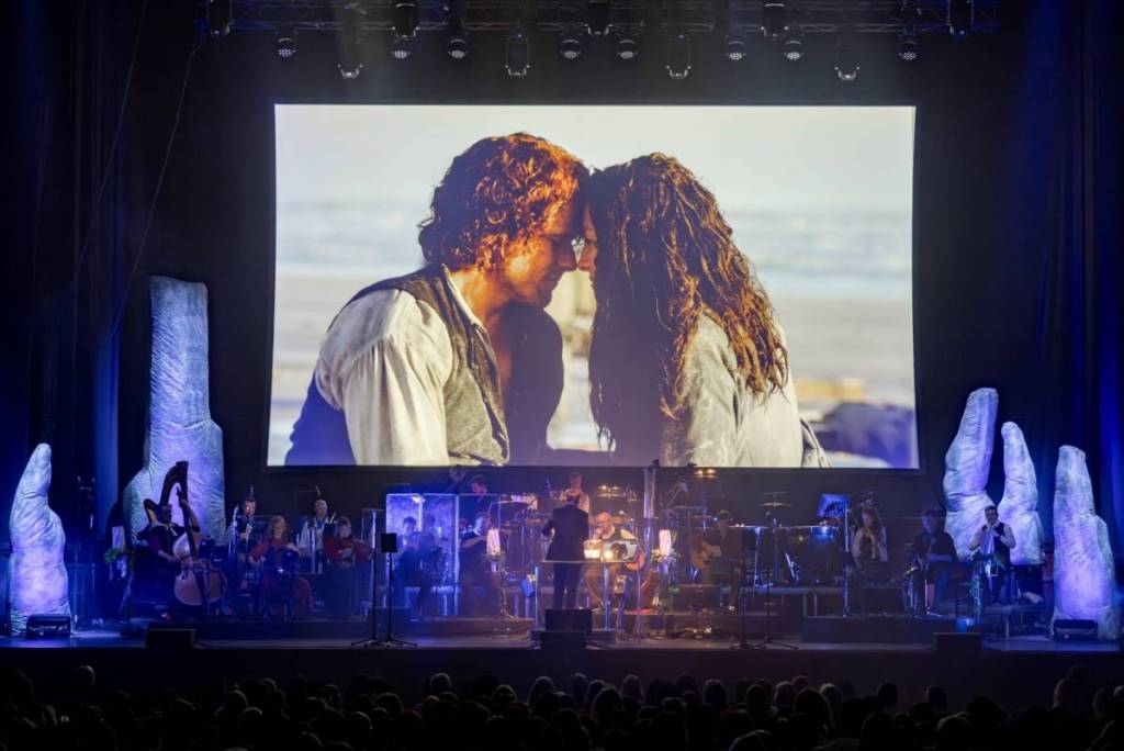 musicians in front of a screen of Jamie and Claire during Outlander in Concert