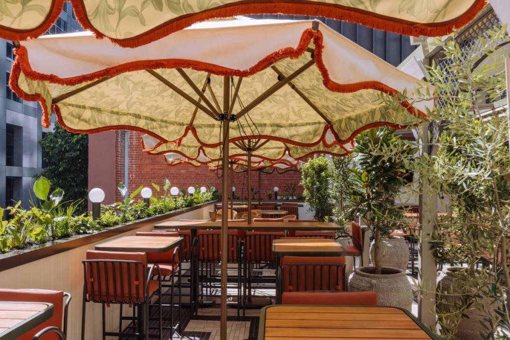 umbrellas over tables next to balcony at Garden State Hotel rooftop
