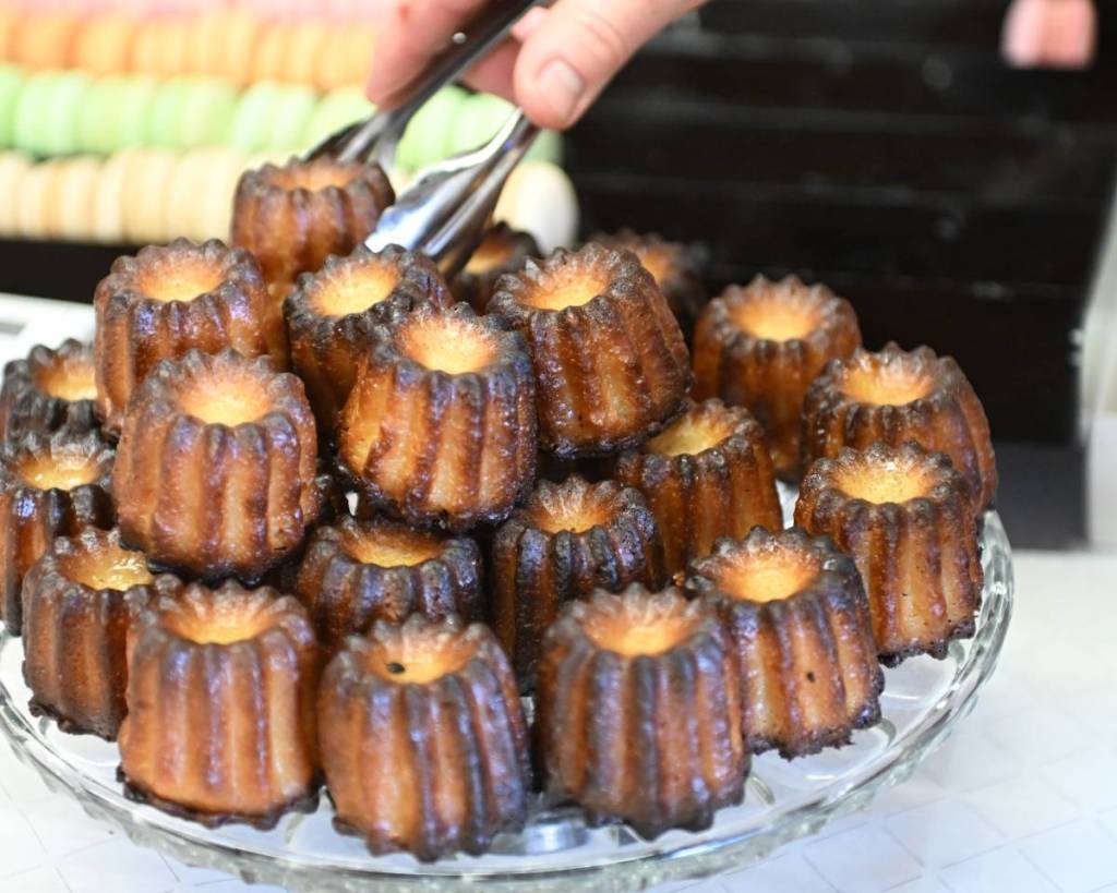 someone using tongs to pick up canelé from stall at Alliance Française Christmas Market
