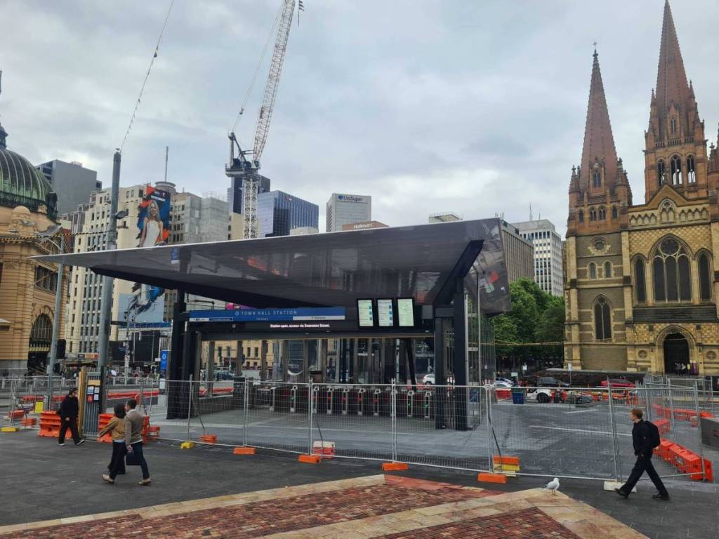 wider view of the Town Hall Station entrance in Fed Square, with construction fence around it