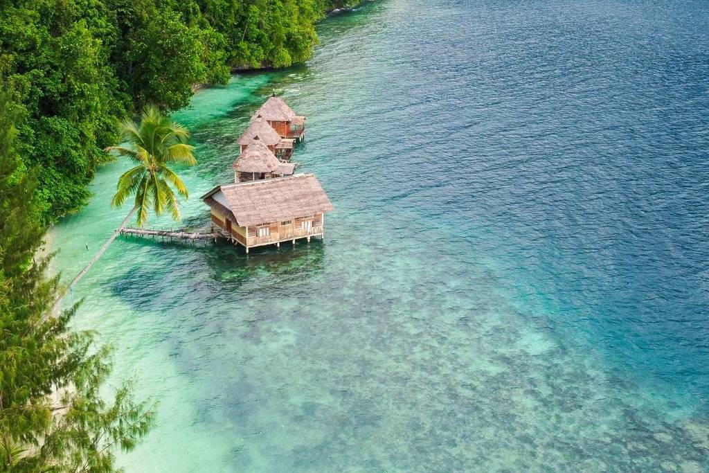 small straw shacks floating in clear blue waters