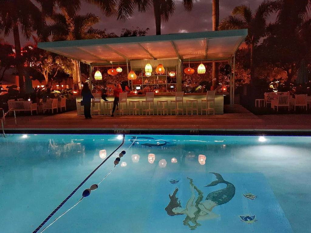 A Miami tiki bar at night with a pool.