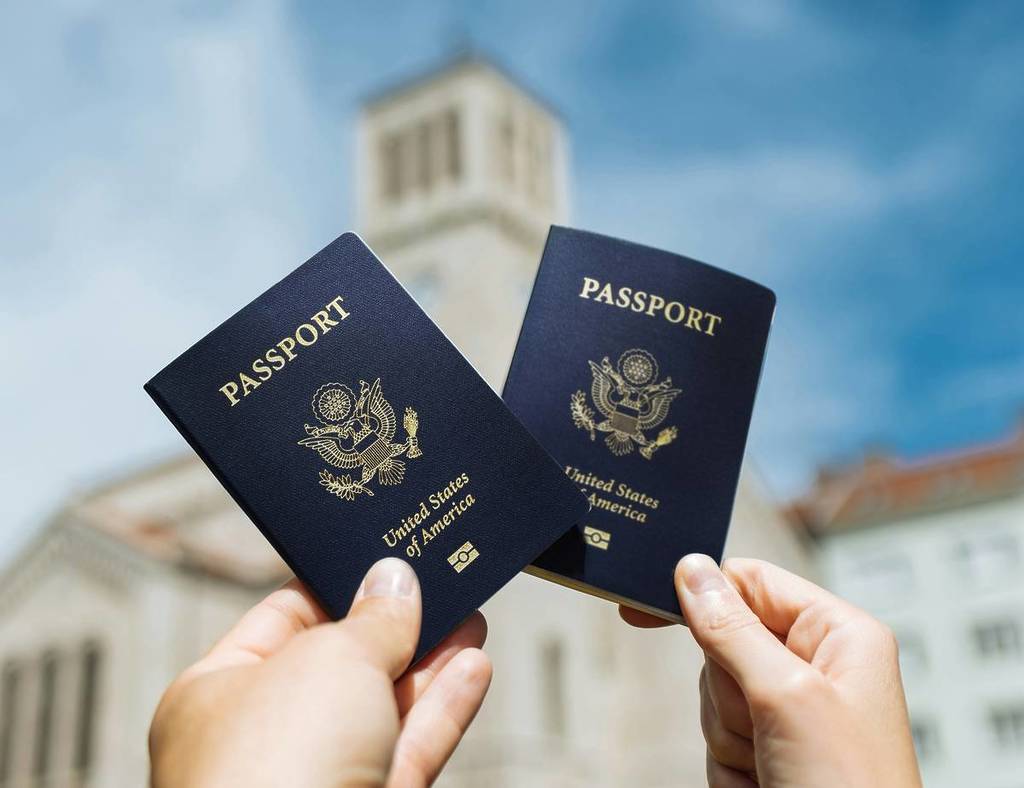 Zwei Personen halten Pässe vor einem Gebäude hoch