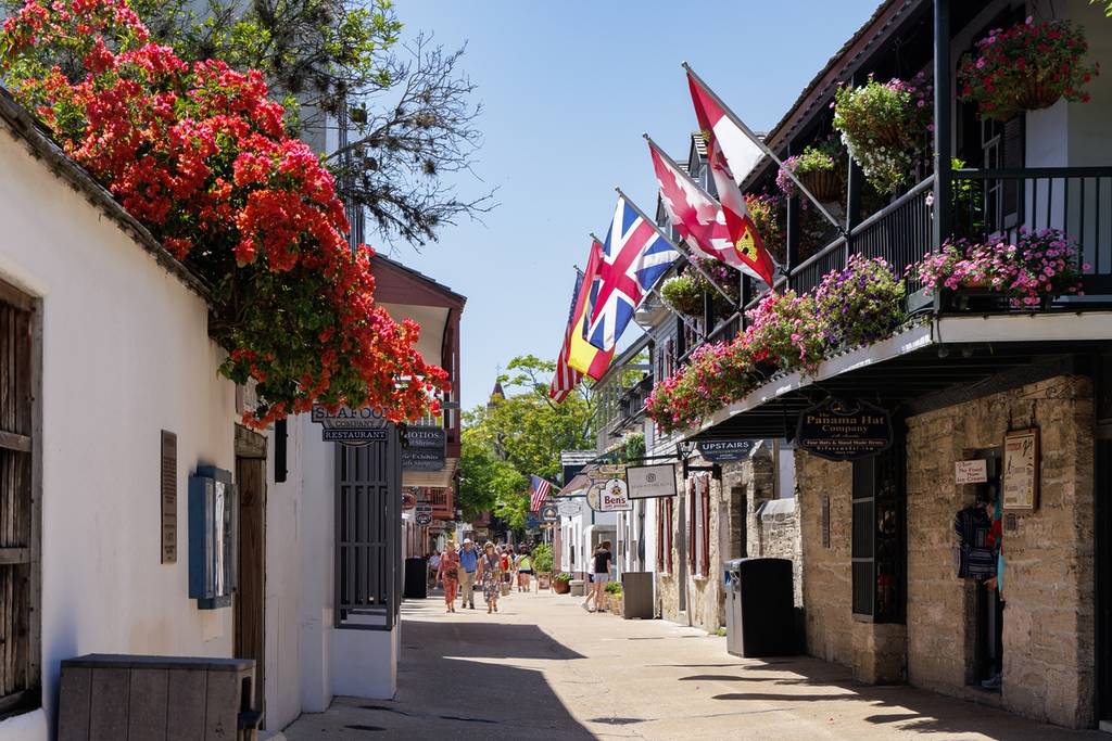 A movimentada St. George Street em St. Augustine, Flórida, repleta de edifícios históricos, bandeiras e flores