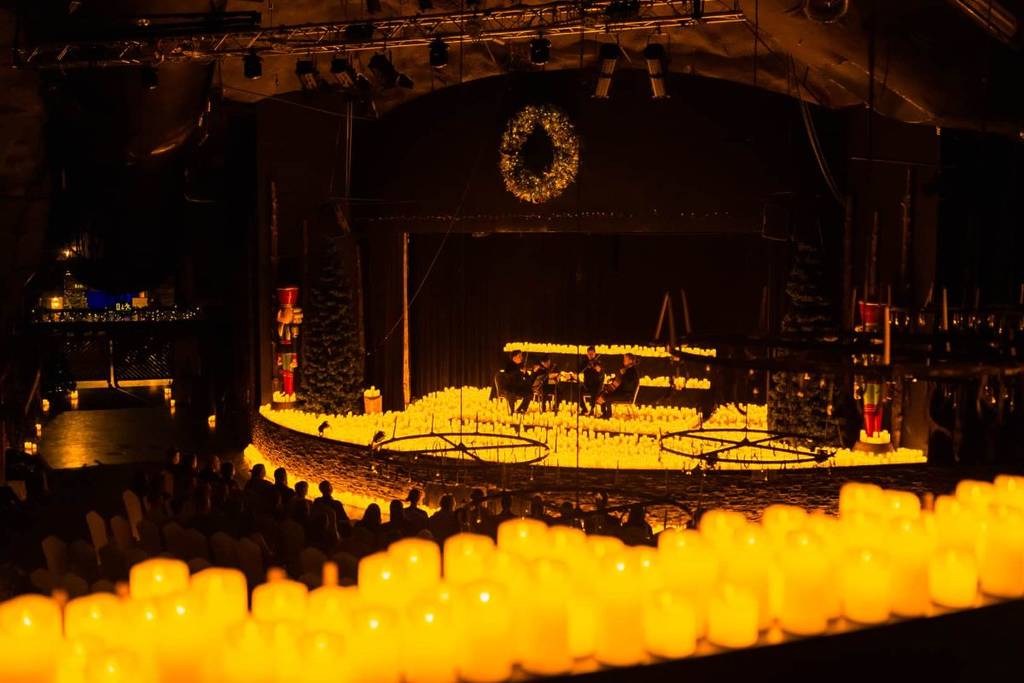 a room is filled with candles and a large wreath hangs from the top of the ceiling