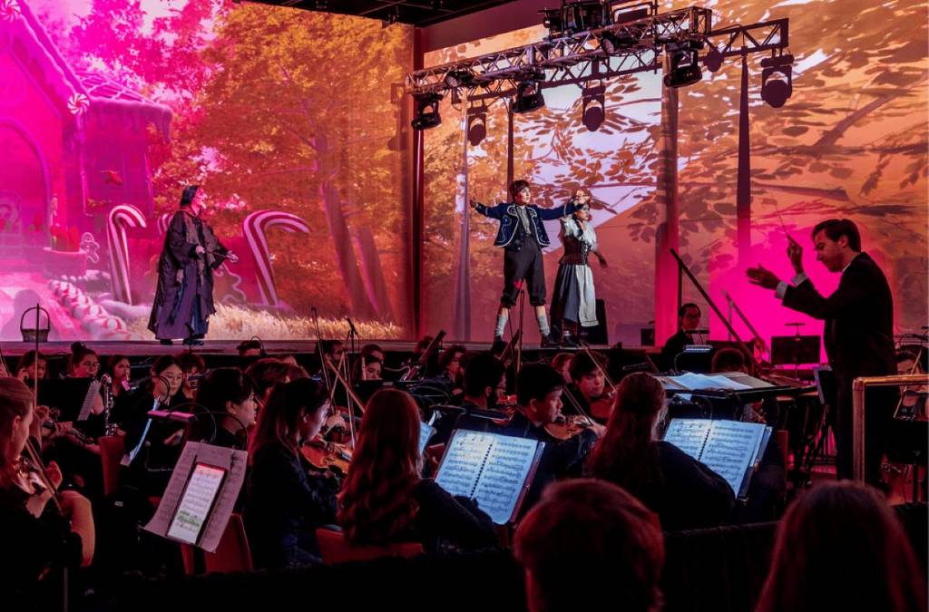 light show reflected behind boy performing on stage at miamim beach festival of lights