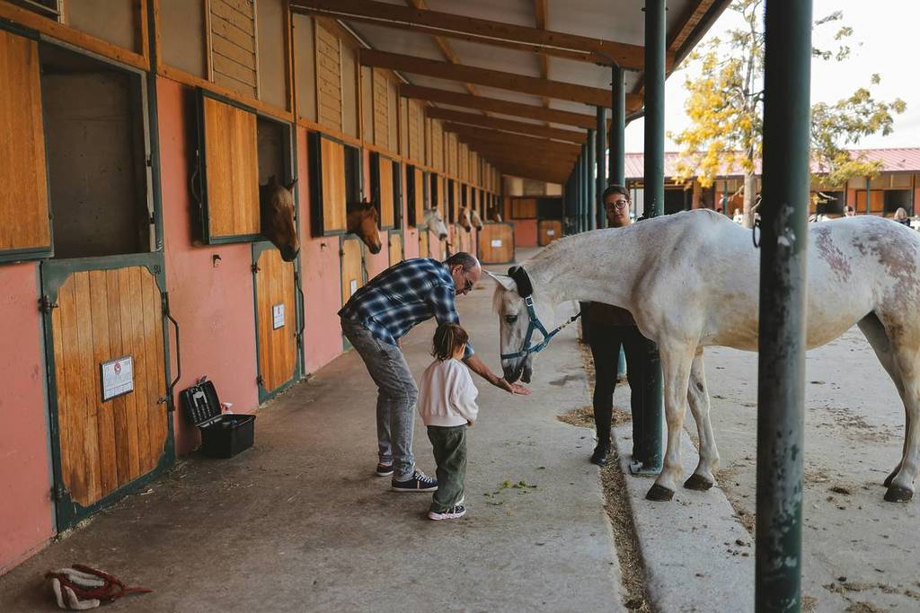 Un hombre y un niño acariciando a un caballo en el establo.