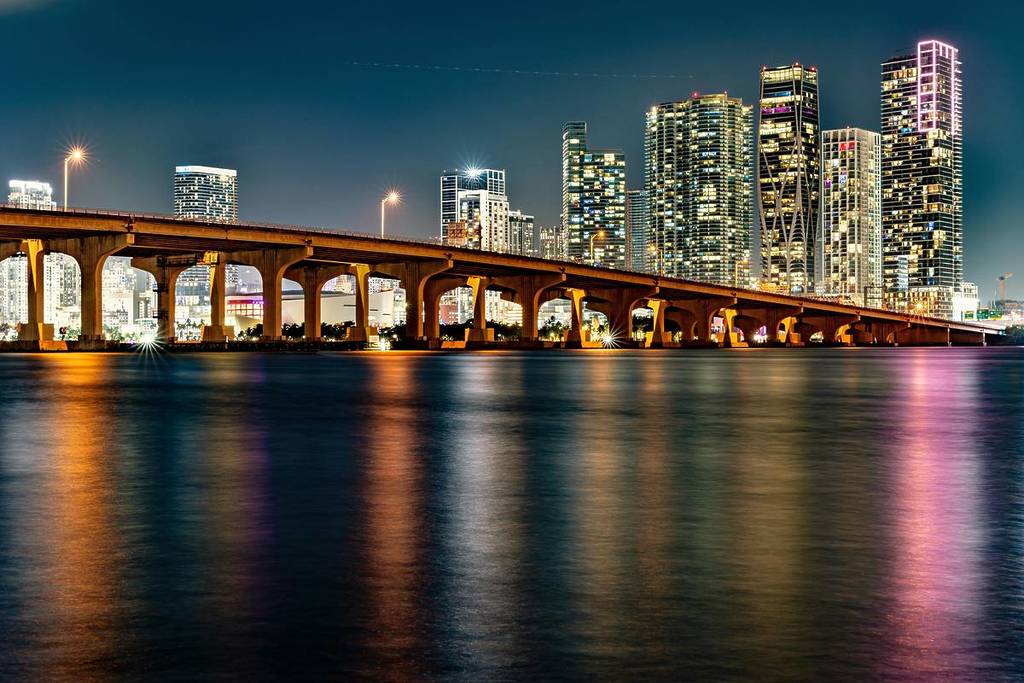 Beleuchtete Skyline von Miami mit einer Brückenreflexion bei Nacht